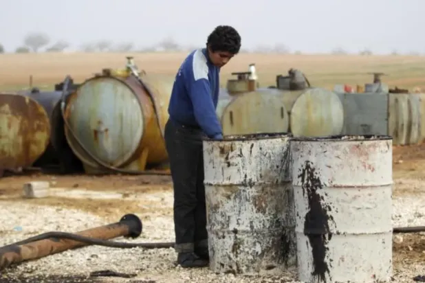 Caption: A youth works at a makeshift oil refinery site in Marchmarin town, southern countryside of Idlib, Syria December 16, 2015. REUTERS/Khalil Ashawi
