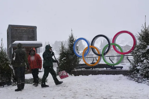 أشخاص يعملون بالقرب من الحلقات الأولمبية المعروضة استعداداً لدورة الألعاب الأولمبية الشتوية 2026 (أ.ب)