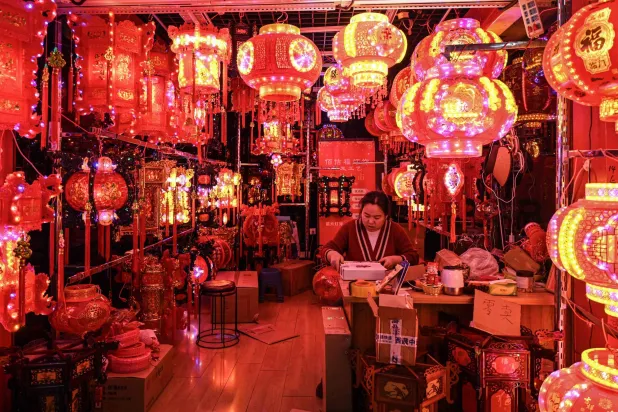 بائع ينتظر الزبائن في كشك لبيع الفوانيس قبل حلول السنة القمرية الجديدة للحصان (أ.ف.ب)