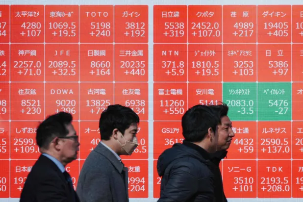 مشاة يمرون أمام شاشة تعرض حركة الأسهم في وسط العاصمة اليابانية طوكيو (أ.ف.ب)