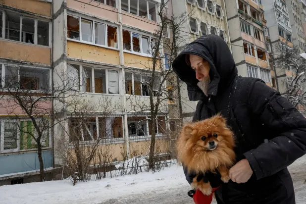 A resident with a dog walks near an apartment building damaged during a Russian overnight drone strike, amid Russia's attack on Ukraine, in Kyiv, Ukraine February 5, 2026. REUTERS/Gleb Garanich 