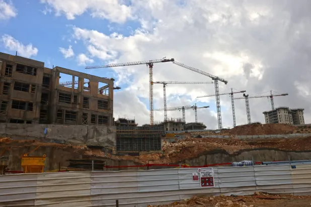 رافعات بناء شاهقة تعلو موقع بناء في جفعات هاماتوس إحدى المستوطنات الإسرائيلية في القدس الشرقية المحتلة (أ.ف.ب)