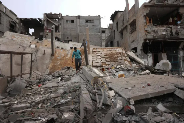 فلسطيني يسير فوق دمار مبنى من 5 طبقات دمرته غارة إسرائيلية في خان يونس جنوب قطاع غزة الجمعة (أ.ف.ب)