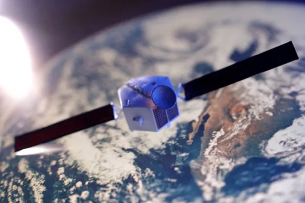 صورة مركبة لنموذج قمر اصطناعي مع خلفية لكوكب الأرض (رويترز)