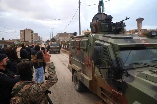 Fighters from the Syrian Democratic Forces welcome a convoy of the Syrian Ministry of Interior heading to Qamishli in northeastern Syria. (AP)