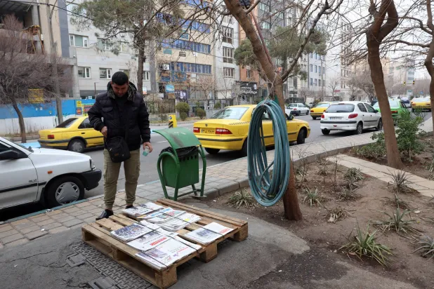 رجل إيراني يطالع العناوين على كشك لبيع الصحف في طهران اليوم (إ.ب.أ)