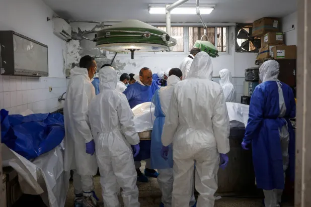 خبراء الطب الشرعي والأطباء يفحصون رفات متوفين من سكان غزة في مستشفى الشفاء (أ.ف.ب)