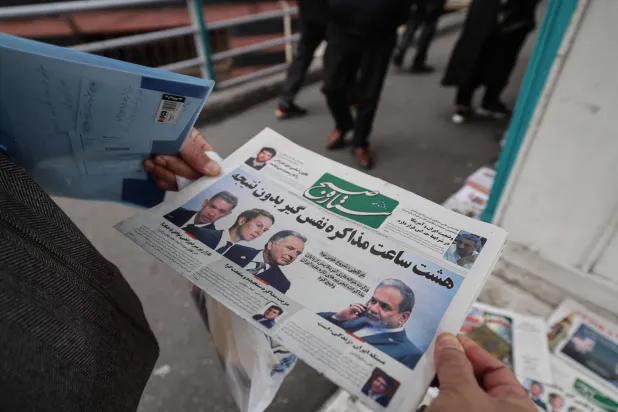رجل في طهران يطالع الصفحة الأولى لصحيفة إيرانية تتناول الجولة الأولى من المفاوضات مع الولايات المتحدة (أ.ف.ب) 