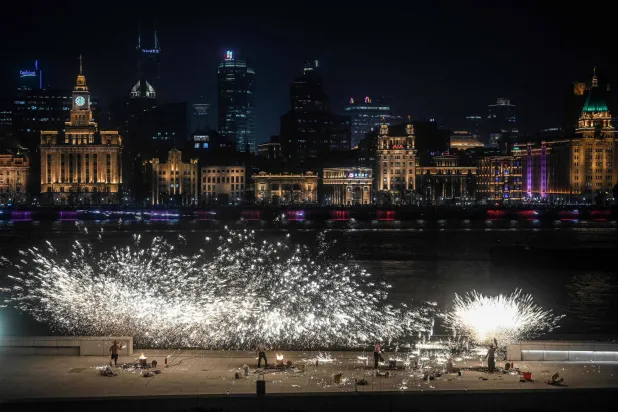  Performers throw molten iron to create sparks during a performance on the Bund promenade along the Huangpu river, ahead of the upcoming Lunar New Year of the Horse in Shanghai on February 2, 2026. (AFP) 