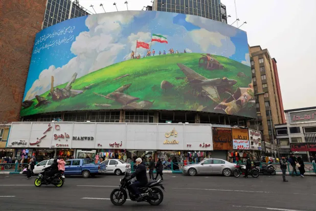 إيرانيون يمرون بجانب لوحة عملاقة مناهضة للولايات المتحدة على مبنى في أحد ميادين طهران ()