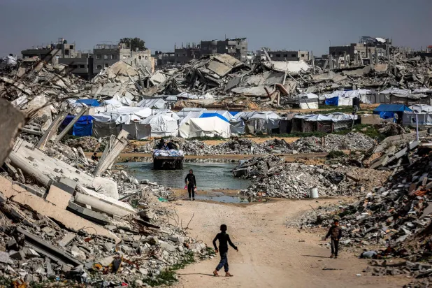Boys walk past the rubble of destroyed buildings in the Jabalia camp for Palestinian refugees in the northern Gaza Strip on February 8, 2026. (Photo by Omar AL-QATTAA / AFP)