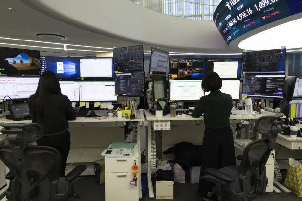 يعمل متداولون كوريون جنوبيون أمام شاشات تعرض مؤشرات الأسهم ببنك هانا في سيول (إ.ب.أ)