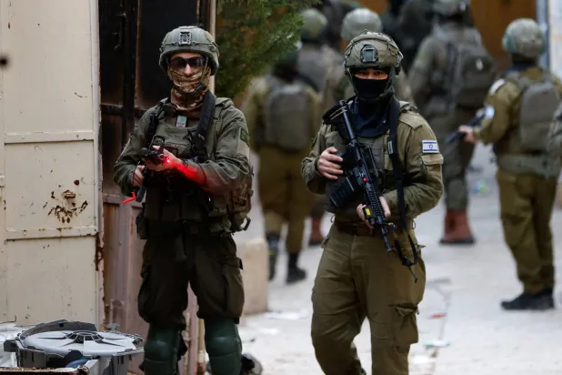  Israeli soldier points his weapon towards the camera, during a weekly settlers' tour in Hebron, in the Israeli-occupied West Bank, February 7, 2026. (Reuters)