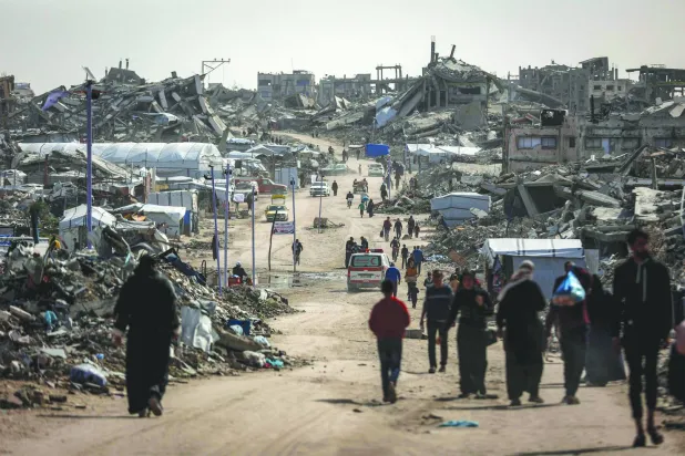 فلسطينيون يمشون وسط المباني المنهارة في مخيم جباليا للاجئين بشمال غزة (أ.ف.ب)
