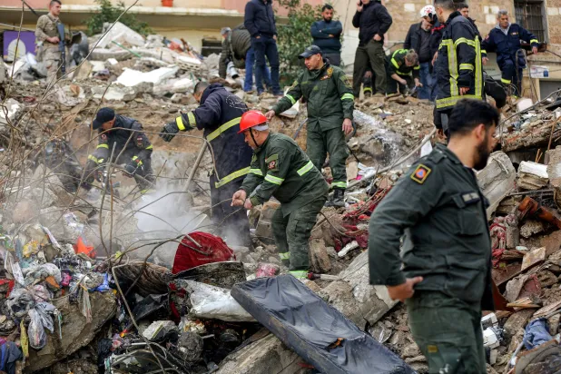 عناصر من الدفاع المدني يرفعون الأنقاض لإنقاذ العالقين تحت مبنيين انهارا في طرابلس شمال لبنان (د.ب.أ)