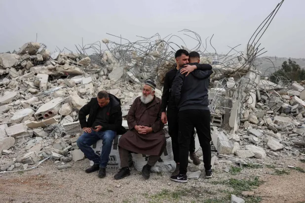 فلسطيني يواسي مواطنه بينما يجلس آخران بين أنقاض منزل هدمته إسرائيل في قرية شقبة غرب مدينة رام الله أمس (أ.ف.ب)
