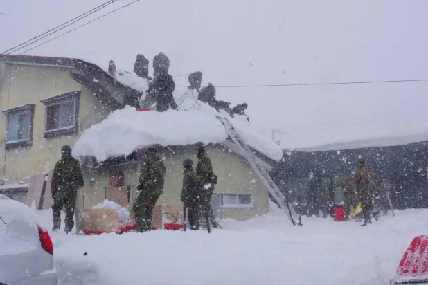 This handout photo taken on February 7, 2026 and received on February 10 from Japan's Ministry of Defense shows members of the Japan Ground Self-Defense Force's 5th Infantry Regiment, stationed in Aomori Prefecture, carrying out snow removal work in a town within Aomori Prefecture. (Photo by Handout / Japan's Ministry of Defense / AFP)  