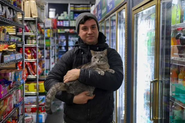 Guest Dan Rimada, founder of Bodega Cats of New York holds a cat named Ashley in a bodega corner store on December 17, 2025 in New York City. (AFP)