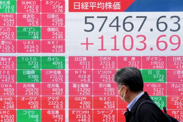 رجل يمر أمام شاشة تعرض حركة الأسهم في وسط العاصمة اليابانية طوكيو (أ.ف.ب)