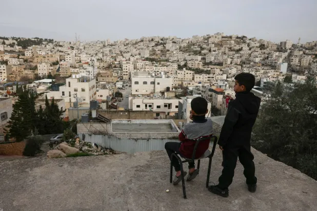 Palestinian boys look out over the Israeli-occupied West Bank city of Hebron from a rooftop on February 9, 2026. (AFP)