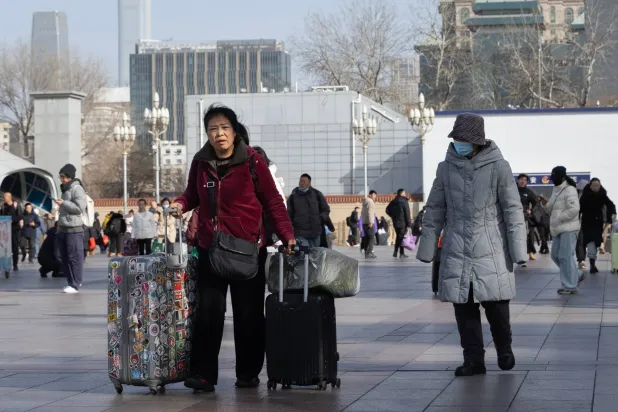 مسافرون خلال فترة أعياد بداية العام الجديد أمام محطة قطارات في العاصمة الصينية بكين (إ.ب.أ)