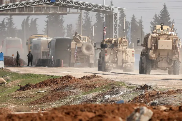 مركبات عسكرية أميركية ترافق حافلات تنقل معتقلي تنظيم «داعش» من سوريا إلى العراق في مدينة القامشلي السورية - 8 فبراير 2026 (رويترز)