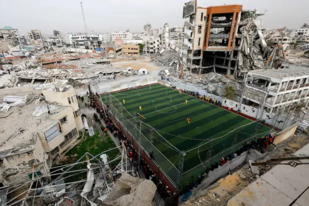 Palestinians play soccer on a pitch, near buildings destroyed during the two-year Israeli offensive, in Gaza City. REUTERS/Mahmoud Issa 