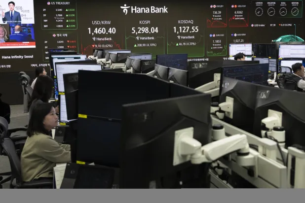 متداولون كوريون جنوبيون يعملون أمام شاشات تعرض مؤشر «كوسبي» ببنك «هانا» في سيول (إ.ب.أ)