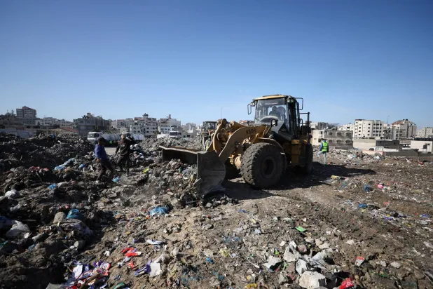 عمّال برنامج الأمم المتحدة الإنمائي بدأوا إزالة النفايات من مكب نفايات ضخم في مدينة غزة (رويترز)