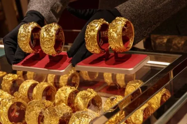 يعرض موظف متجر أزواجاً من أساور الذهب المخصصة للأعراس الصينية بمحل مجوهرات في هونغ كونغ (رويترز)