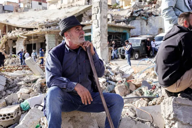 لبناني من سكان بلدة كفركلا الحدودية مع إسرائيل في جنوب لبنان ينتظر وصول رئيس الحكومة نواف سلام للبلدة المدمرة جراء الحرب خلال زيارة له الأحد إلى المنطقة (أ.ف.ب)