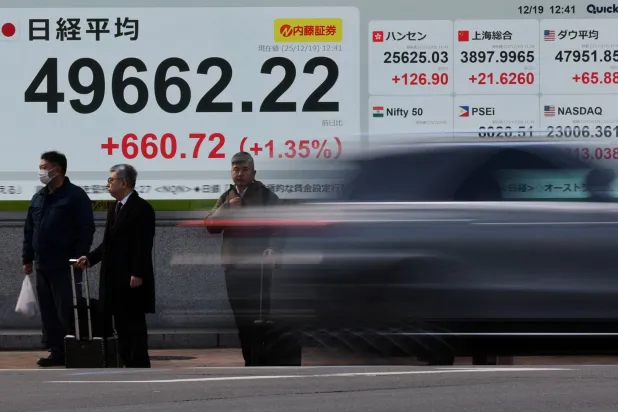 مواطنون يابانيون يقفون بأحد شوارع طوكيو امام لوحة تنقل أرقام مؤشر "نيكاي" المالي (رويترز)