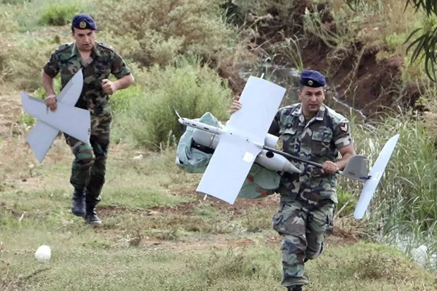 عنصران من الجيش اللبناني ينقلان حطام مسيَّرة إسرائيلية سقطت فوق جنوب لبنان في 2024 (أرشيفية - رويترز) 