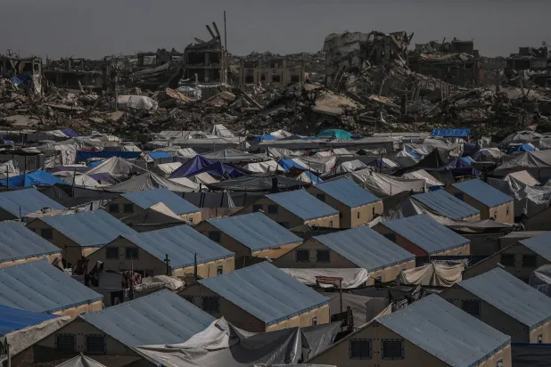 خيام تؤوي مئات النازحين وفي الخلفية الدمار الهائل بعد عامين من القصف الإسرائيلي في حي الزيتون شرق مدينة غزة (إ.ب.أ)