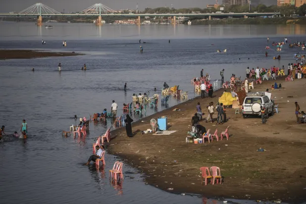 عائلات تتجمع بجانب المياه الضحلة لنهر النيل في جزيرة توتي حيث يلتقي النيلان الأزرق والأبيض في الخرطوم (أرشيفية - أ.ف.ب)