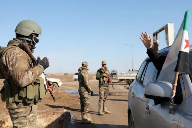 Haseke’nin güneyindeki Şeddadi’de yaşayan bir kişi, geçtiğimiz ay şehrin kontrolünü ele geçiren Suriye ordusu askerlerine el sallıyor. (AFP)