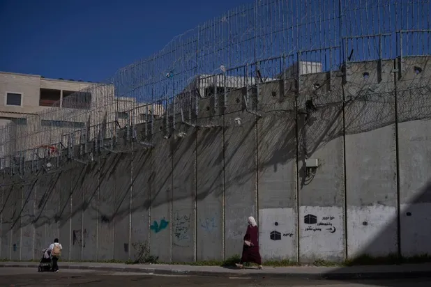  Palestinians walk along the separation barrier between the West Bank and east Jerusalem neighborhood of Beit Hanina, Sunday Feb. 15, 2026. (AP)