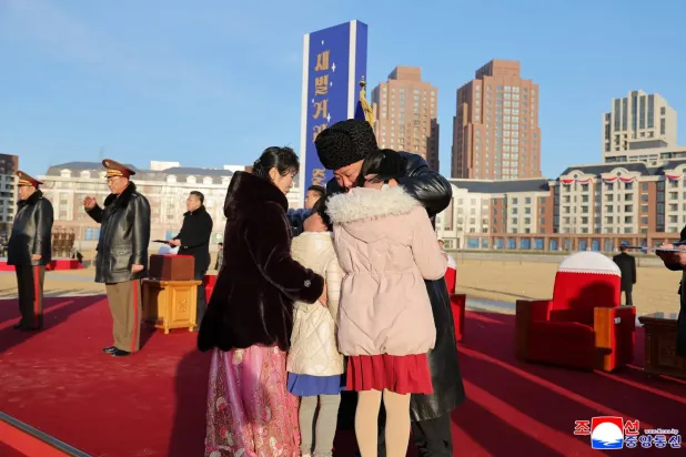 Kuzey Kore lideri Kim, Pyongyang'da yeni bir konut mahallesinin açılışında, savaşta hayatını kaybeden bir askerin aile üyelerine sarılırken (Reuters)