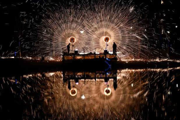 Men perform molten iron fireworks in a park in Beijing on February 15, 2026 ahead of the Lunar New Year of the Horse. (Photo by Pedro PARDO / AFP)