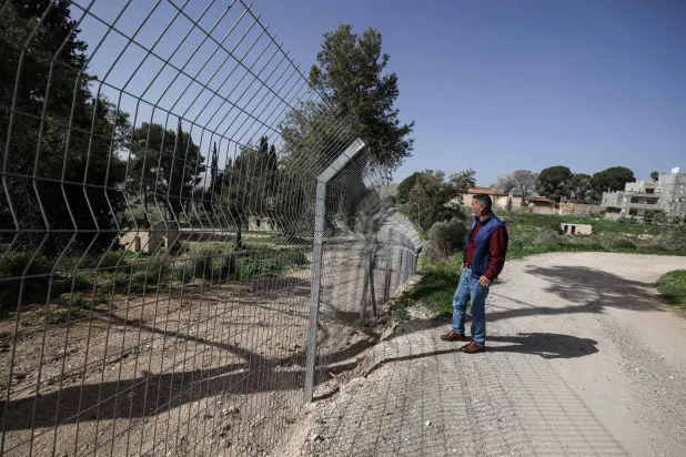 فلسطيني يقف عند سياج أقامه مستوطنون يهود بعد إعلان سيطرتهم على محطة قطار المسعودية التاريخية شمال مدينة نابلس مباشرةً بالضفة الغربية (أ.ف.ب)