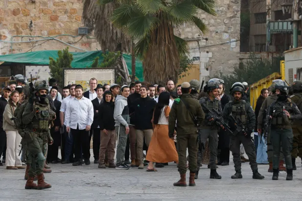 جنود إسرائيليون يقفون حراساً خلال جولة أسبوعية للمستوطنين في الخليل بالضفة الغربية (رويترز)