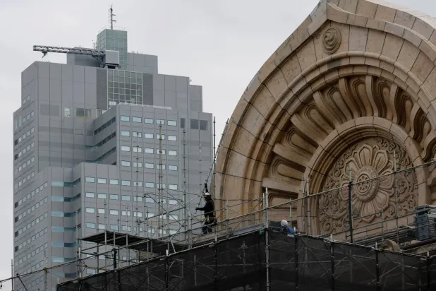 عامل يقوم بتنظيف سطح أحد المباني القديمة في العاصمة اليابانية طوكيو (رويترز)