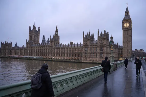 Pedestrians cross Westminster Bridge in front of Parliament during the early morning hours in London, Tuesday, Feb. 10, 2026.(AP Photo/Kin Cheung)