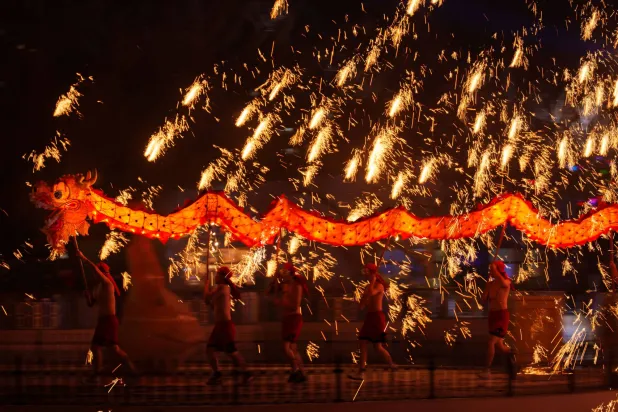 Fire performers carry a dragon during a molten iron fireworks performance known as "fire dragon steel flowers" ahead of Lunar New Year celebrations at an amusement park on the outskirts of Beijing, China, Saturday, Feb. 14, 2026. (AP Photo/Vincent Thian)