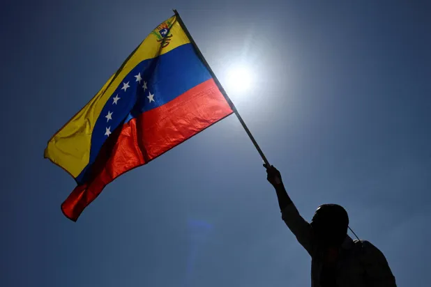 A man holds up a Venezuelan flag while taking part in a march calling for amnesty for political prisoners and to mark Youth Day, in Caracas, Venezuela, February 12, 2026. (Reuters)