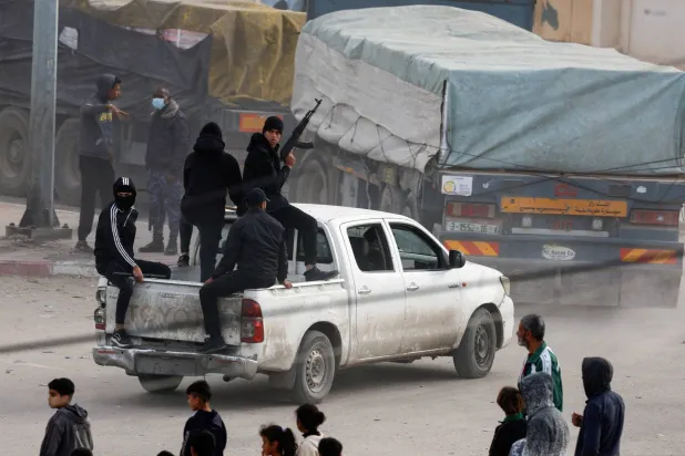 Security personnel guard trucks carrying aid as they arrive in Rafah, amid the ongoing conflict between Israel and the Palestinian Islamist group Hamas, in the southern Gaza Strip January 17, 2024. (Reuters)