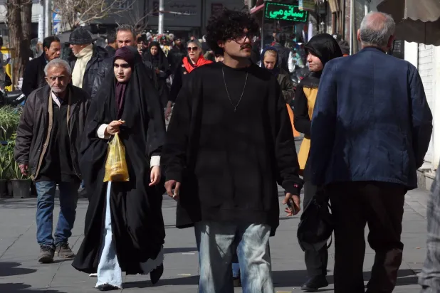 Iranians walk on a street in Tehran, Iran, 16 February 2026. (EPA)