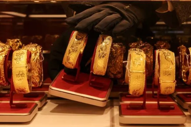 موظف يعرض زوجاً من الأساور الذهبية المخصّصة لحفلات الزفاف الصينية داخل محل للمجوهرات في هونغ كونغ (رويترز)