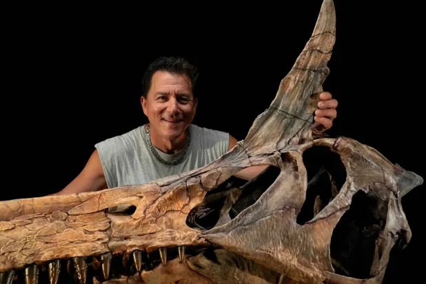 Paleontologist Paul Sereno poses in his Fossil Lab at the University of Chicago with a reconstructed skull of the dinosaur Spinosaurus mirabilis. The photograph was released by the University of Chicago on February 19, 2026. Keith Ladzinski/Handout via REUTERS