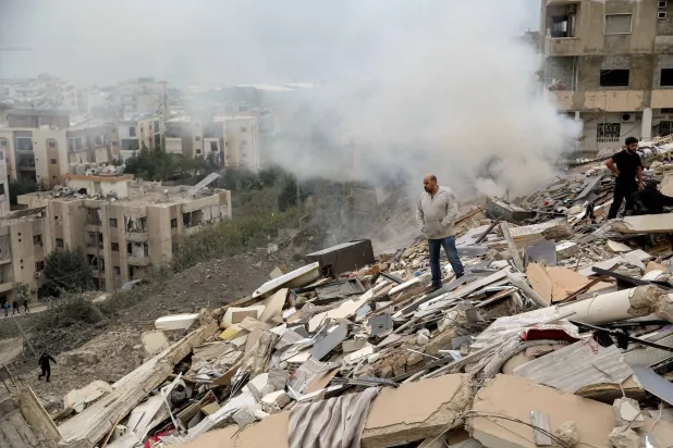 22 January 2026, Lebanon, Qnarit: People inspect the damage of a building that was destroyed by an Israeli air raid on the southern Lebanese village of Qnarit. (dpa)